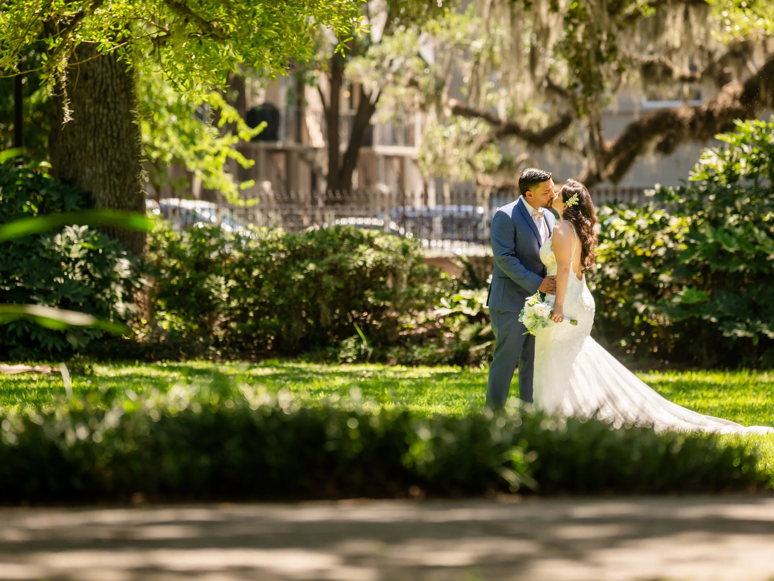 Couple kissing on the lawn beneath moss-draped live oaks in Forsyth Park — Savannah, GA