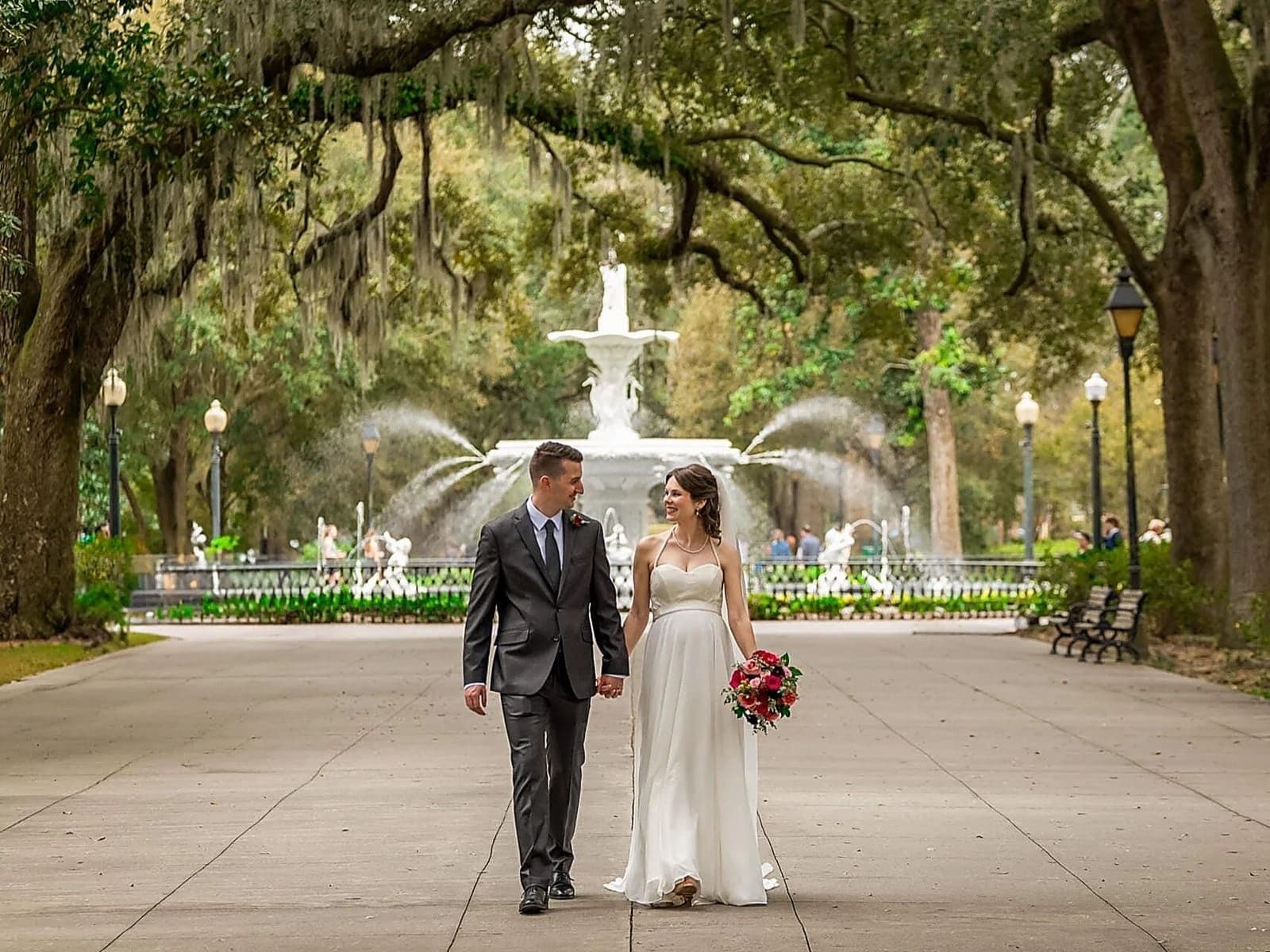 Couple eloping in Savannah, Georgia under draped Spanish moss in a historic square — all-inclusive Savannah elopement package by Elopements Inc.
