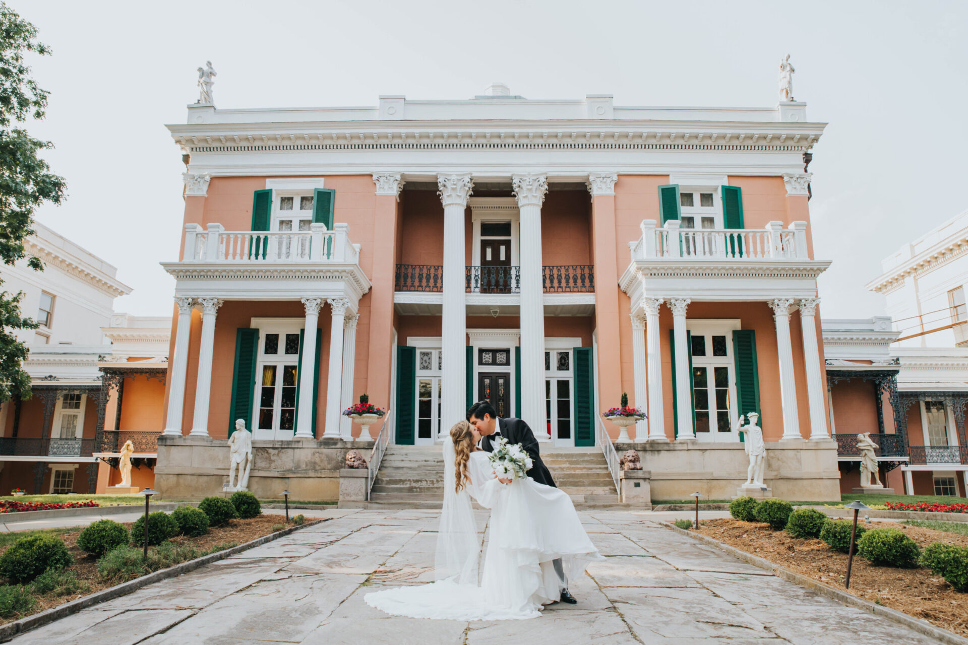 A bride and groom share a kiss in front of Belmont Mansion.